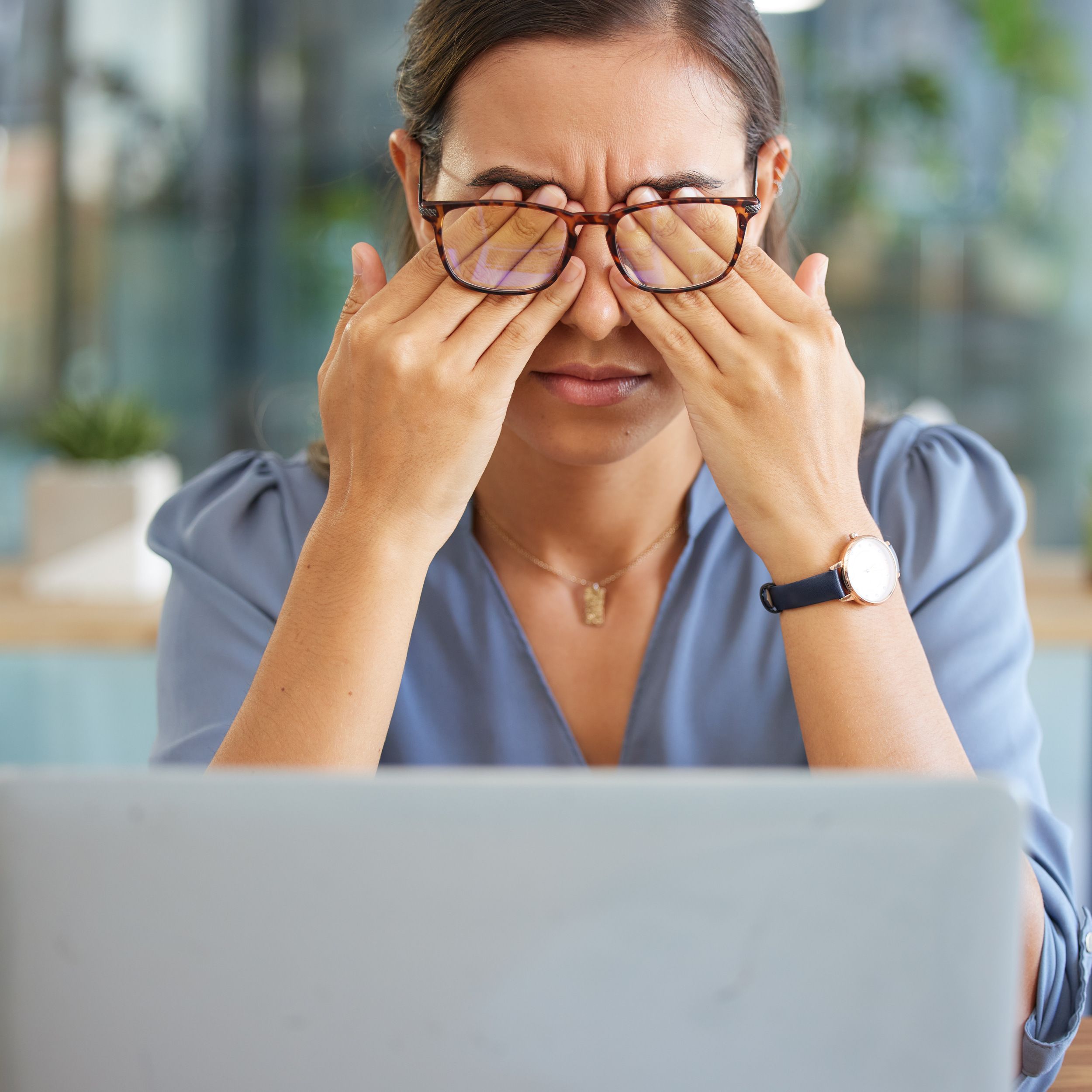 Office worker experiencing eye strain at a laptop