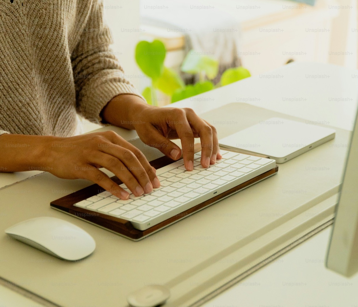 Hands typing on a wireless keyboard at a desk